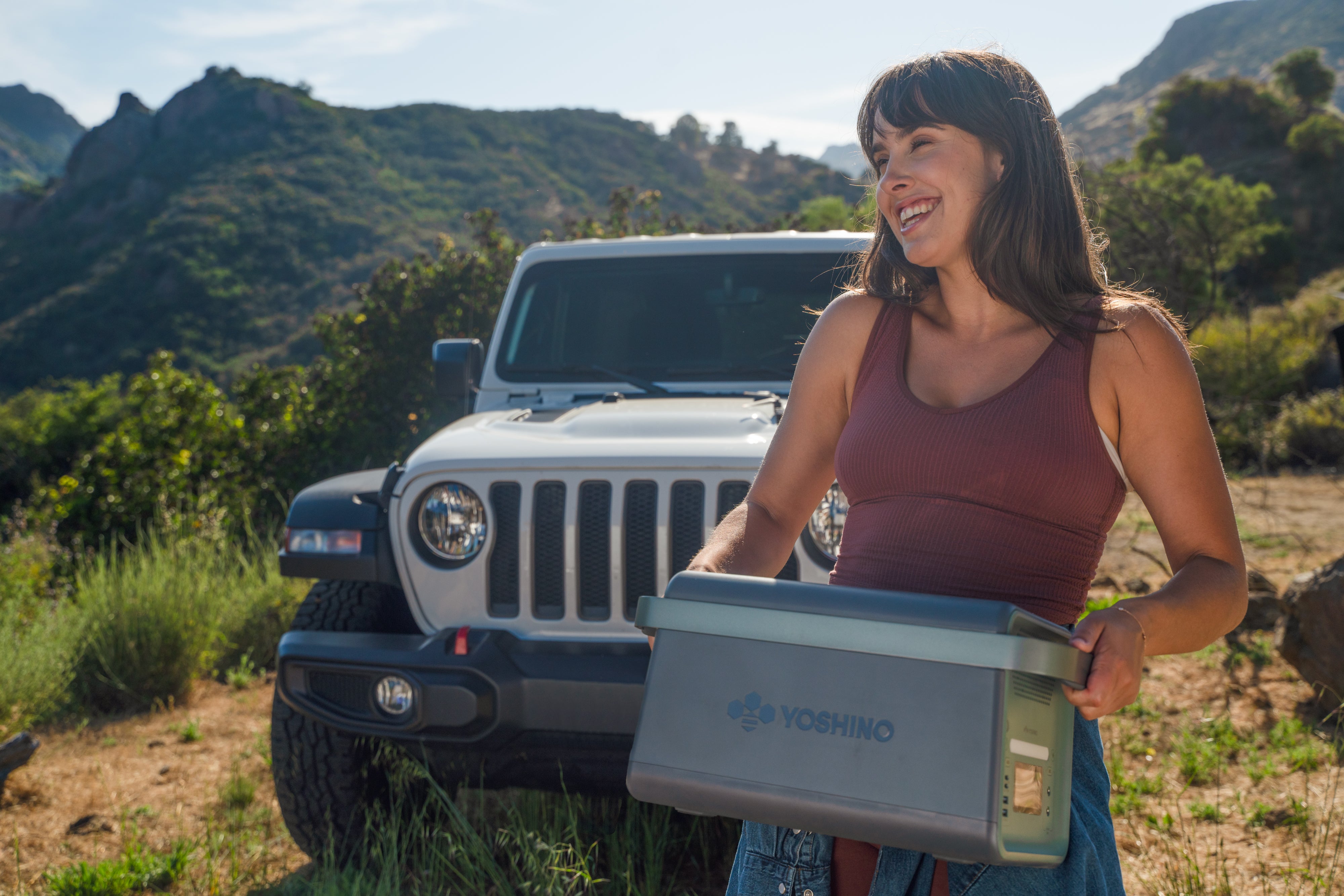 Young Girl Smiling Outdoors Holding Yoshino B2000 Power Station with White Jeep Wrangler